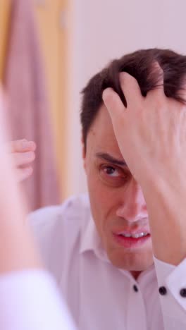 Worried man examining hair loss in bathroom mirror