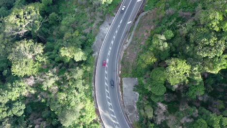 disparo de dron de arriba hacia abajo siguiendo a los autos que circulan por una carretera de montaña