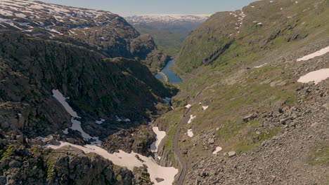 Above-snow-capped-mountain-pass-winding-down-from-summit-to-the-river-in-valley