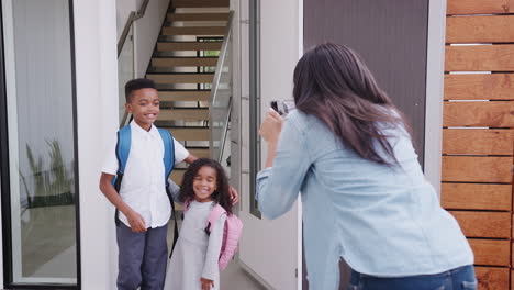 mother taking photo of children with cell phone on first day back at school