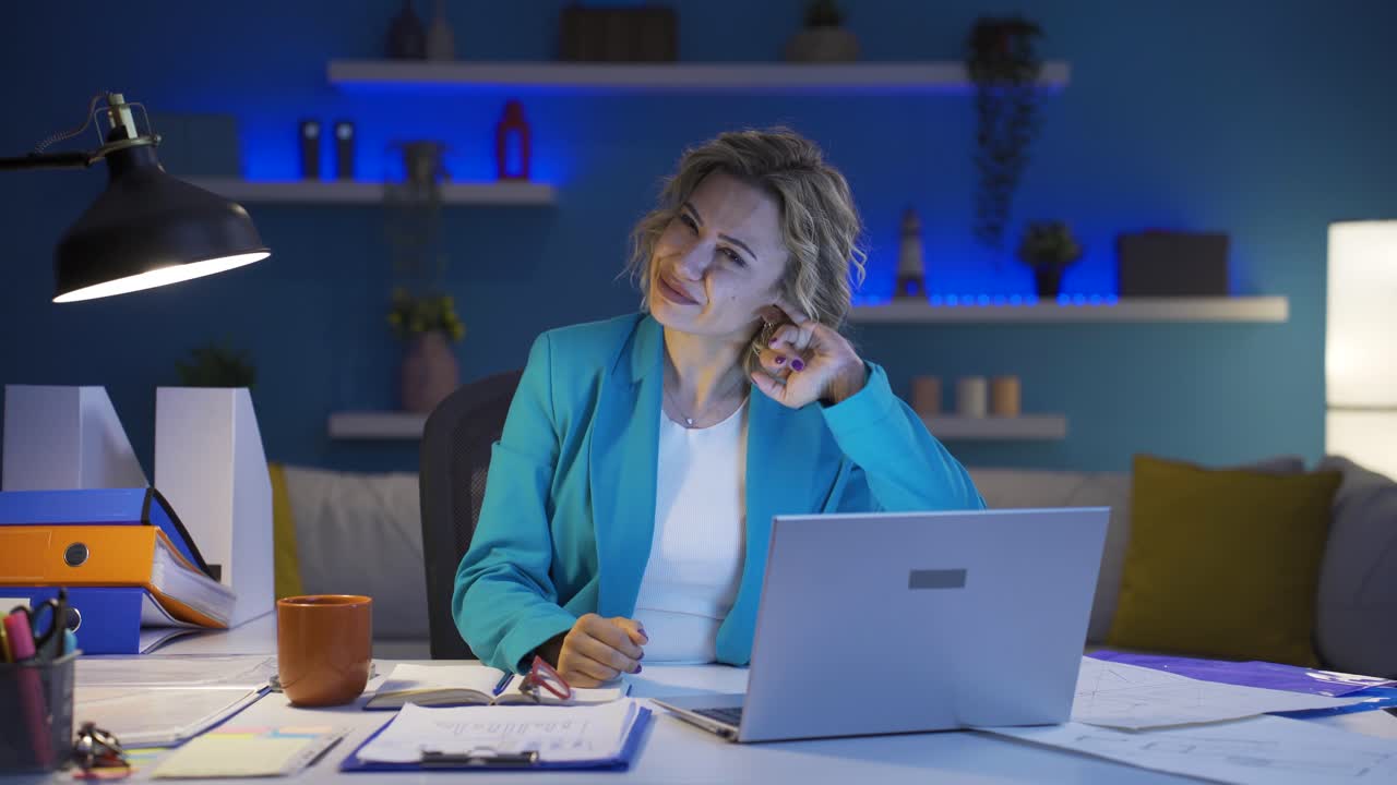 Home office worker woman scratches her ears looking at camera.