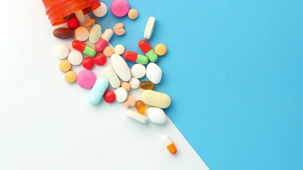 Assorted Pills and Capsules Spilled from an Orange Bottle
