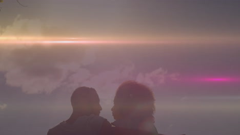 sitting together, silhouetted couple with colorful light animation over cloudy sky