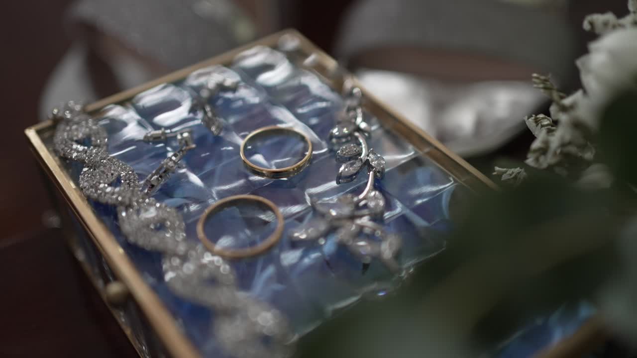 Close up of wedding rings and sparkling jewelry in a decorative glass box