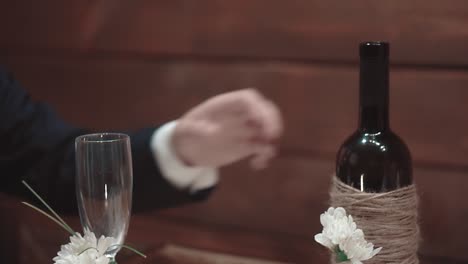 young man takes a bottle of wine from a table in a restaurant close-up slow motion