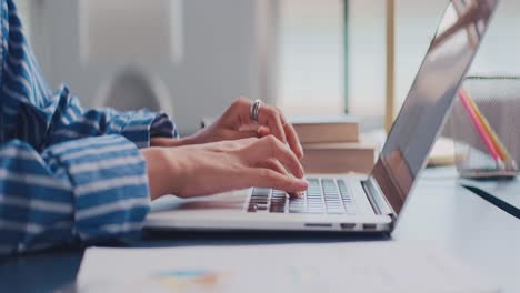 close up of female hands typing on modern laptop keyboard making notes writing