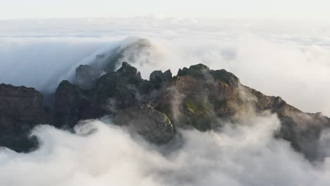 aerial shot of a mountain top with fast moving clouds all around in madeira, early morning