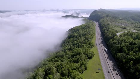 clouds and fog along with traffic on interstate 75 near jellico, tennessee in the cumberland mountains with drone video moving down wide