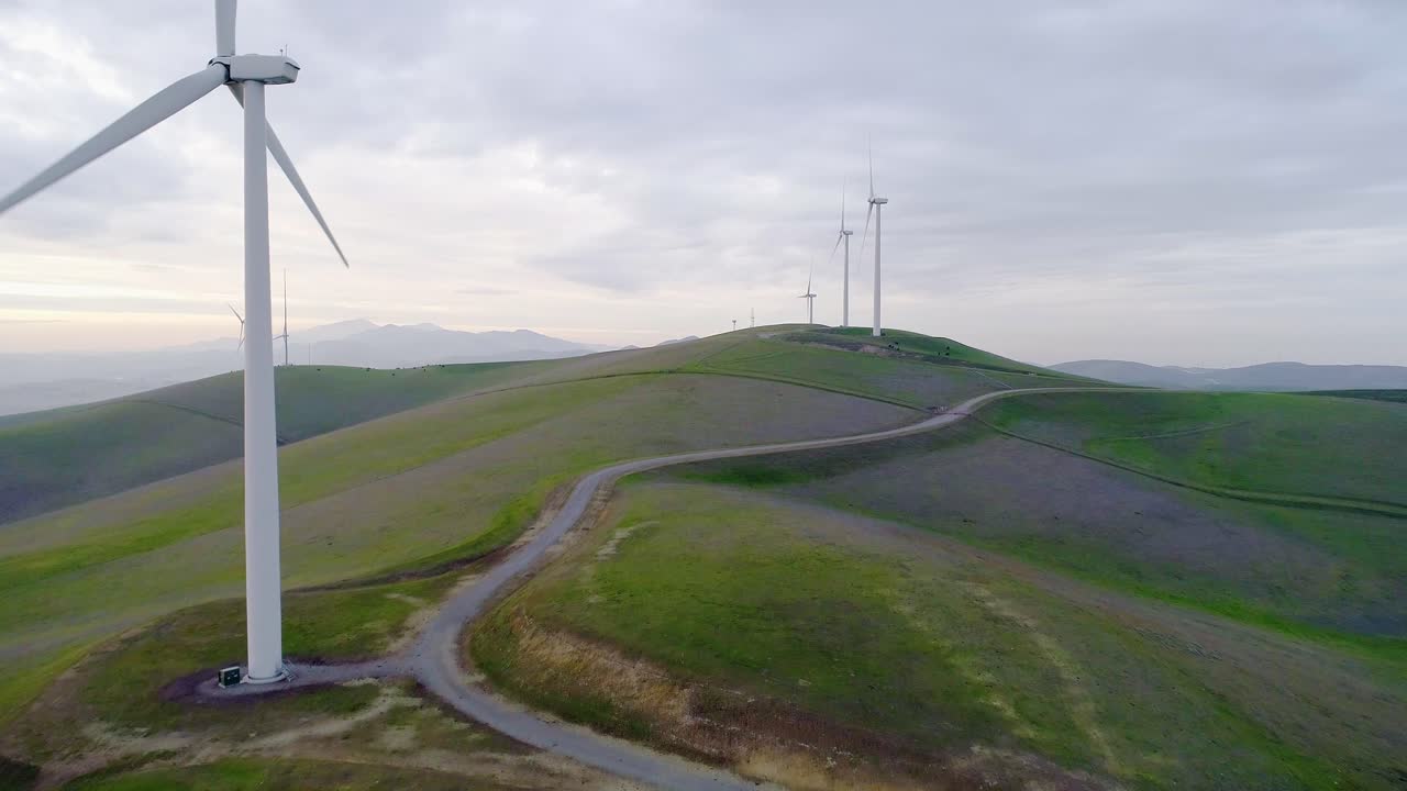 Forward Dolly Tilt Up Shot of Wind Turbines with Moody Clouds at Dusk