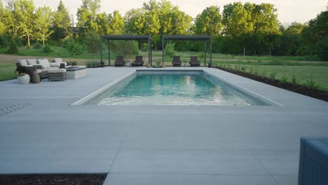 clean symmetrical shot of backyard fiberglass pool and twin pergolas under soft light