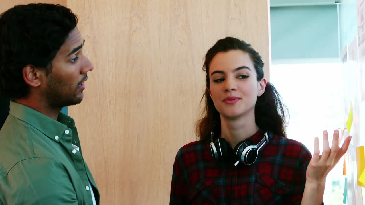 colegas discutiendo sobre las notas adhesivas en la oficina