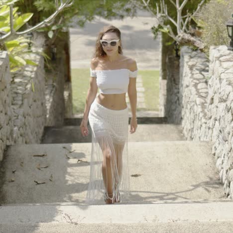 slim female walking on steps in garden