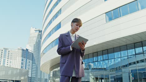 businesswoman using tablet in front of modern building