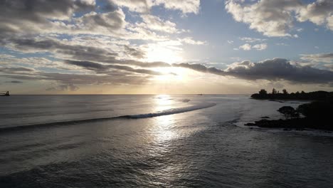 amazing sun setting behind the clouds above rolling waves