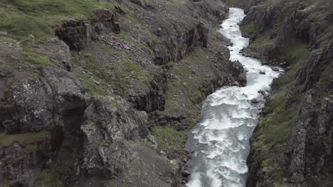 vol aérien à travers une vallée sauvage avec des rapides d'eau vive et des falaises rocheuses