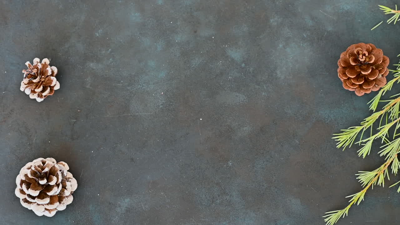 las manos femeninas muestran un regalo envuelto decorado con un cono de pino, una rama y nieve pintada en un fondo negro