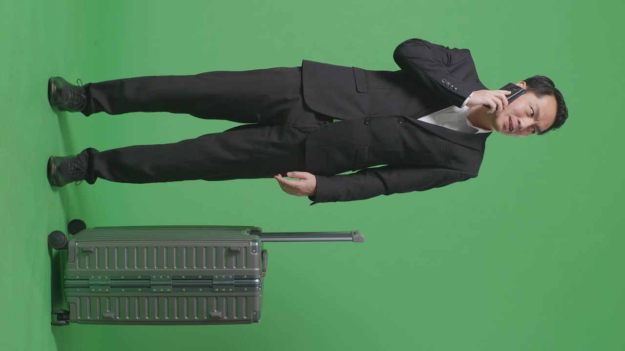 녹색 화면 배경 스튜디오에 서 있는 동안 스마트폰에 대화하는 짐과 함께 아시아 사업가 여행자의 전체 몸