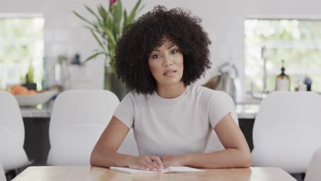 happy african american woman sitting at table, having video call, slow motion