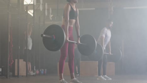 Diverse-man-and-woman-lifting-barbells,-free-weight-training-at-gym,-in-slow-motion