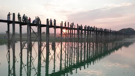 puesta de sol roja ardiente detrás del puente u-bein con gente caminando, antena