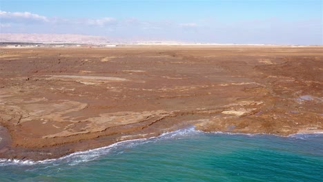 aerial view of dead sea shoreline with cracked earth and sinkholes