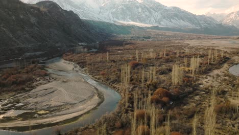 aerial flying over sweeping landscape of ghizer valley of gilgit baltistan with snow capped mountains in the distance