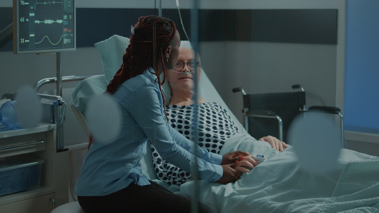African american friend visiting elder patient in hospital ward