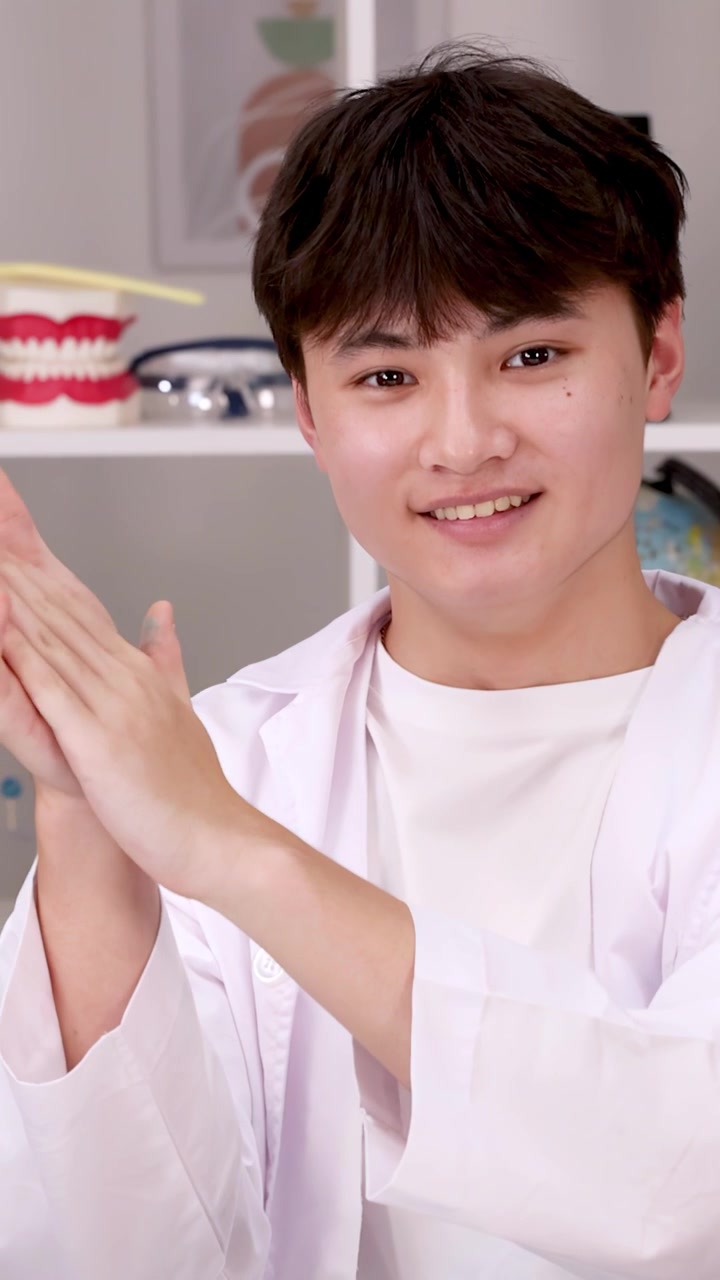 Happy student in white lab coat claps hands while smiling in a science laboratory setting.