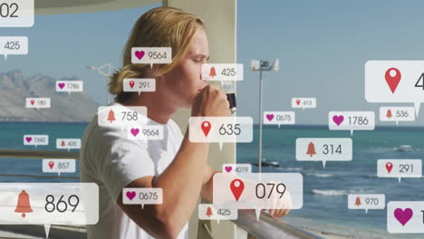 social media notifications animation over person drinking coffee by ocean