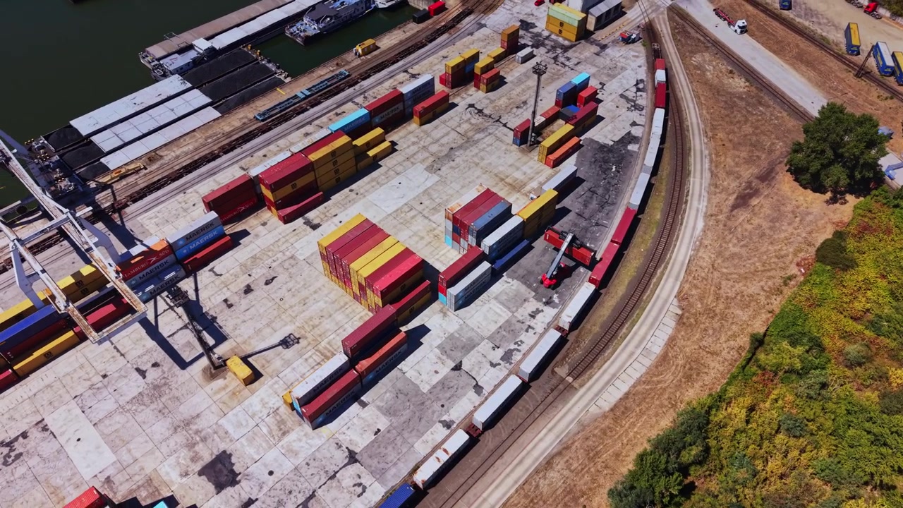 Container yard with trucks and cargo near railway tracks