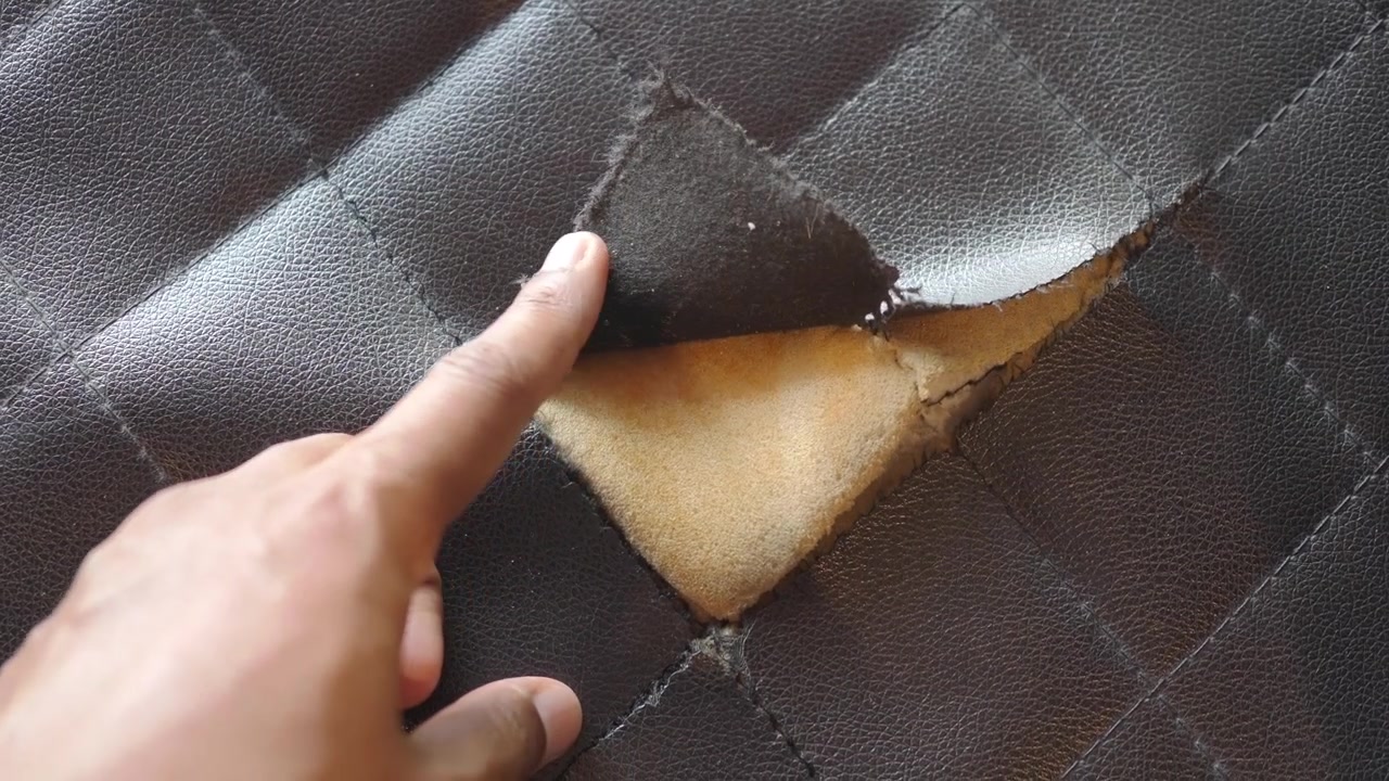 Primer plano de tapicería de cuero dañada con acolchado de espuma visible