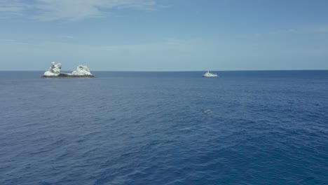humpback whale spouts air with dive boat and revillagigedo islands in background