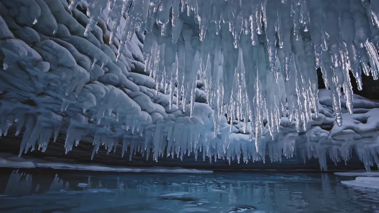 Wide-angle shot of a mesmerizing ice cave with hanging icicles and a frozen lake, capturing a serene