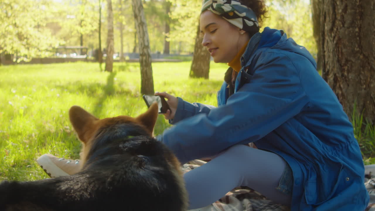 Young Woman Calling Corgi for Taking Selfie in Park
