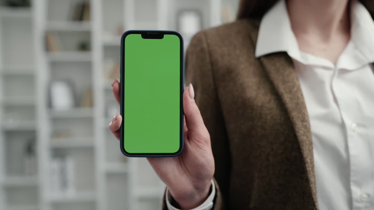 A woman showing a mobile phone with green screen
