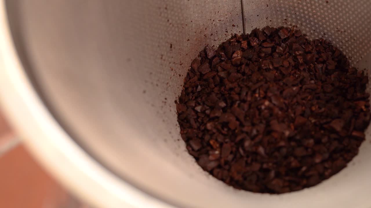 Pouring coffee grounds into strainer