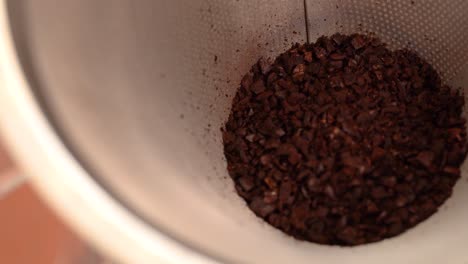 pouring coffee grounds into strainer
