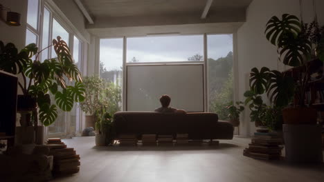 person relaxing in a bright living room surrounded by plants