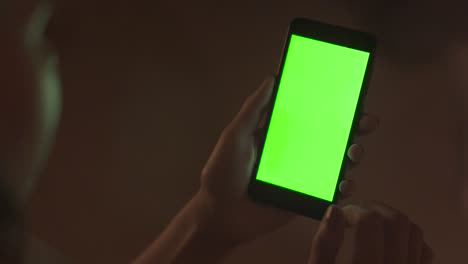 persona que sostiene un teléfono inteligente con pantalla verde