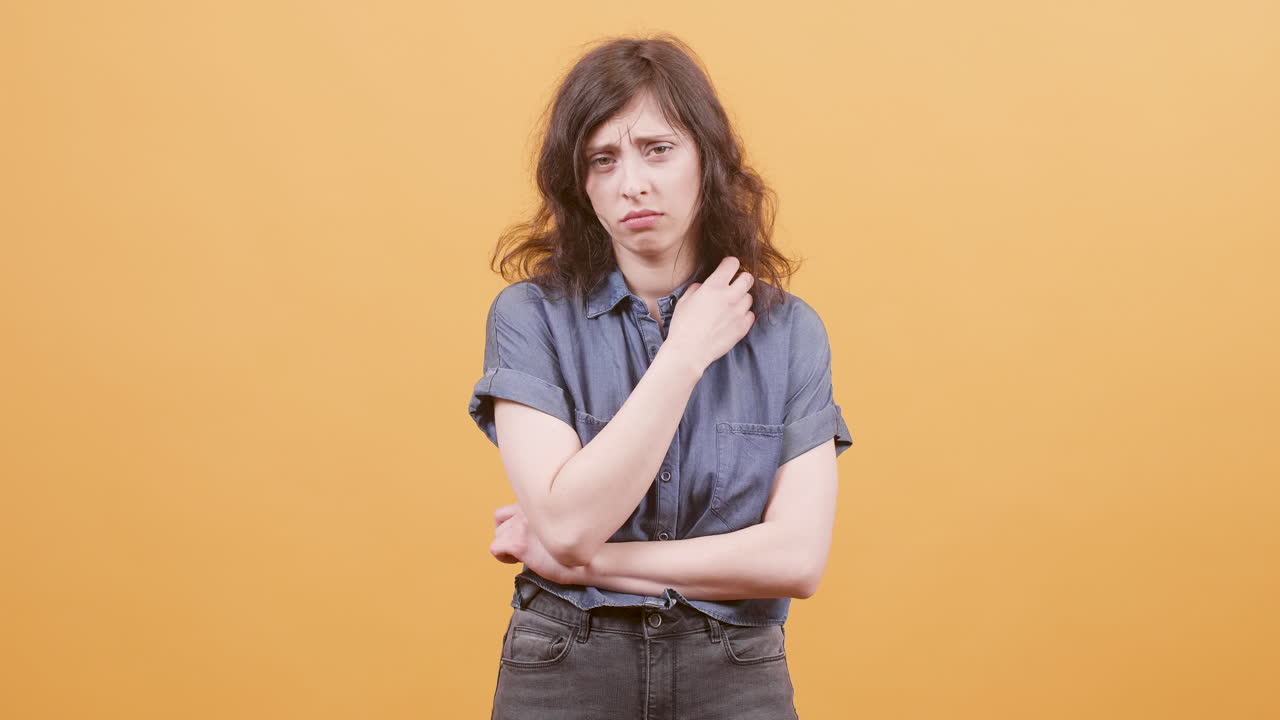 A sad woman is seen against an orange background