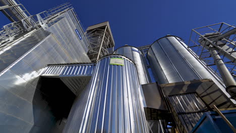 metallic warehouse outdoors. large aluminium containers against blue sky. modern equipment for agribusiness. exterior of new plant.