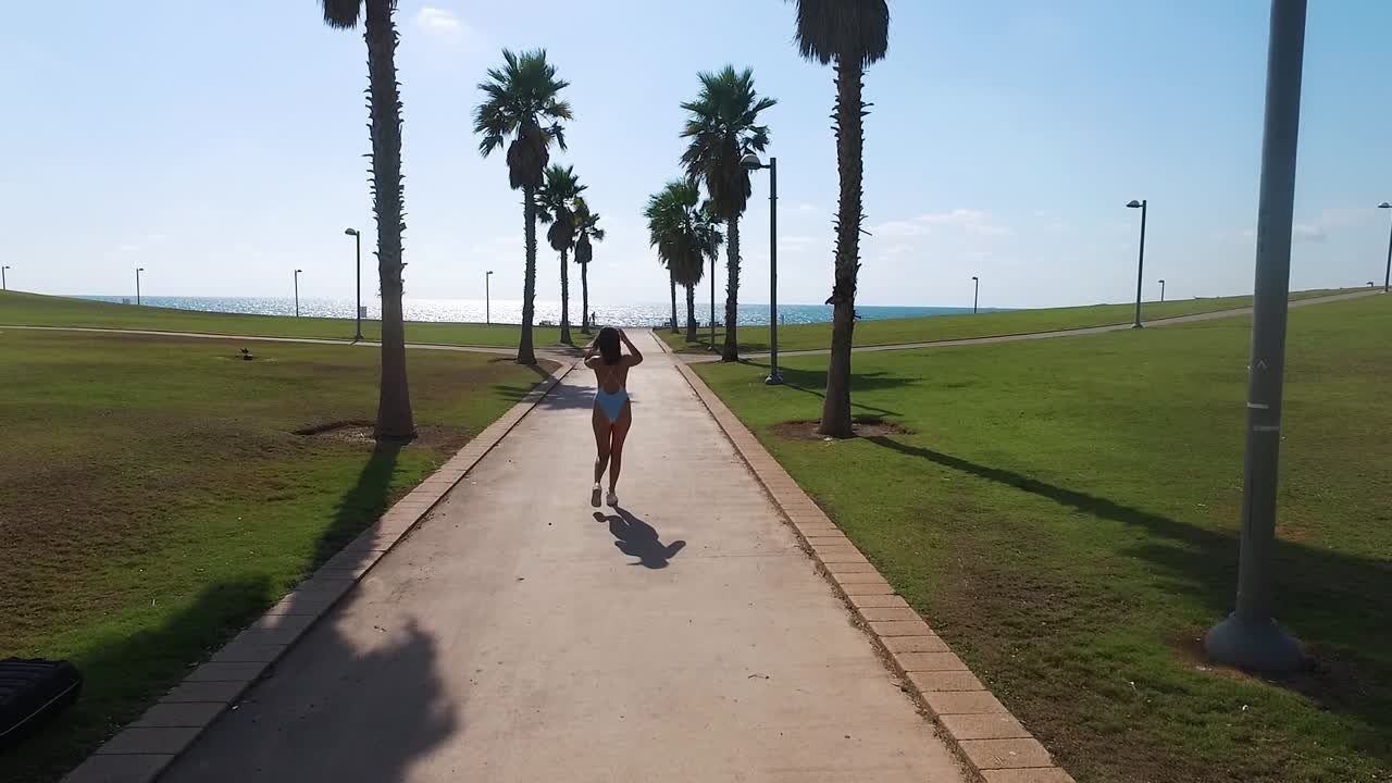 Ragazza che cammina tra le palme. Slow motion da drone