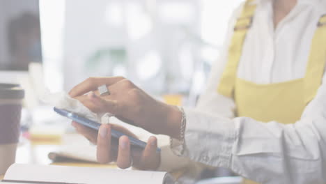 animation of flashing words with woman disinfecting smartphone in office wearing face masks