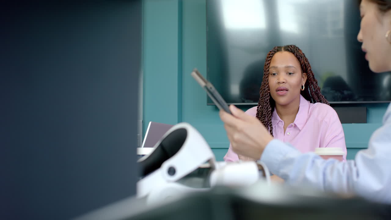 Using smartphone, woman in office meeting with colleagues, discussing work