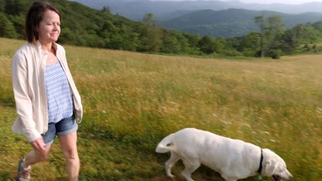 Woman-walks-with-white-lab-with-mountain-backdrop