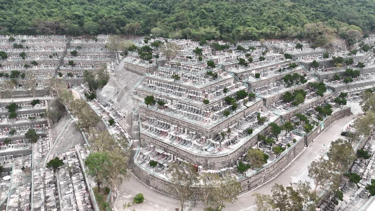 Vista aerea con drone del cimitero di Pok Fu Lam a Hong Kong, che cattura tombe sulle colline, vegetazione e la disposizione panoramica del cimitero urbano dall'alto.