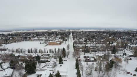 aerial view tracking backwards over an empty road in a snowy manitoba town