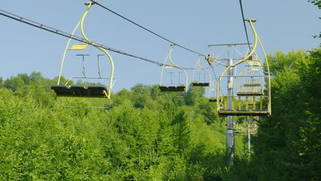 Seats-Of-The-Ski-Lift-They-Move-Upwards-Against-The-Background-Of-A-Forest-Covered-With-A-Forest-Hol