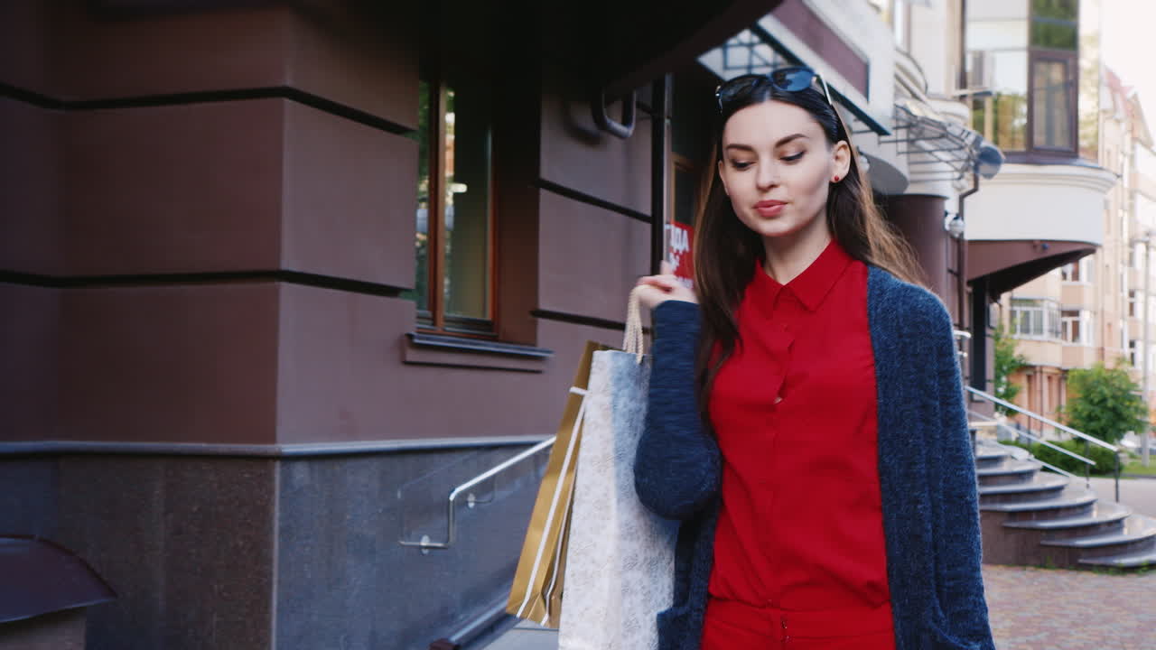 steaicam은 도시에서 쇼핑백을 들고 세련된 여성을 쐈습니다.