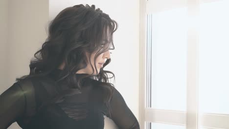 young-woman-with-nice-dark-curly-hair-looks-out-window